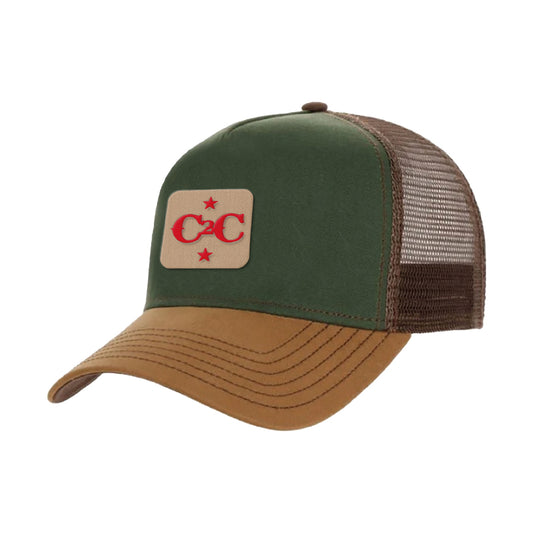 The C2C Country To Country Store Trucker Cap features a green and brown design with a brown suede bill, breathable mesh back, and a tan patch with two red stars and interlocking red Cs—an ideal unique and stylish accessory.