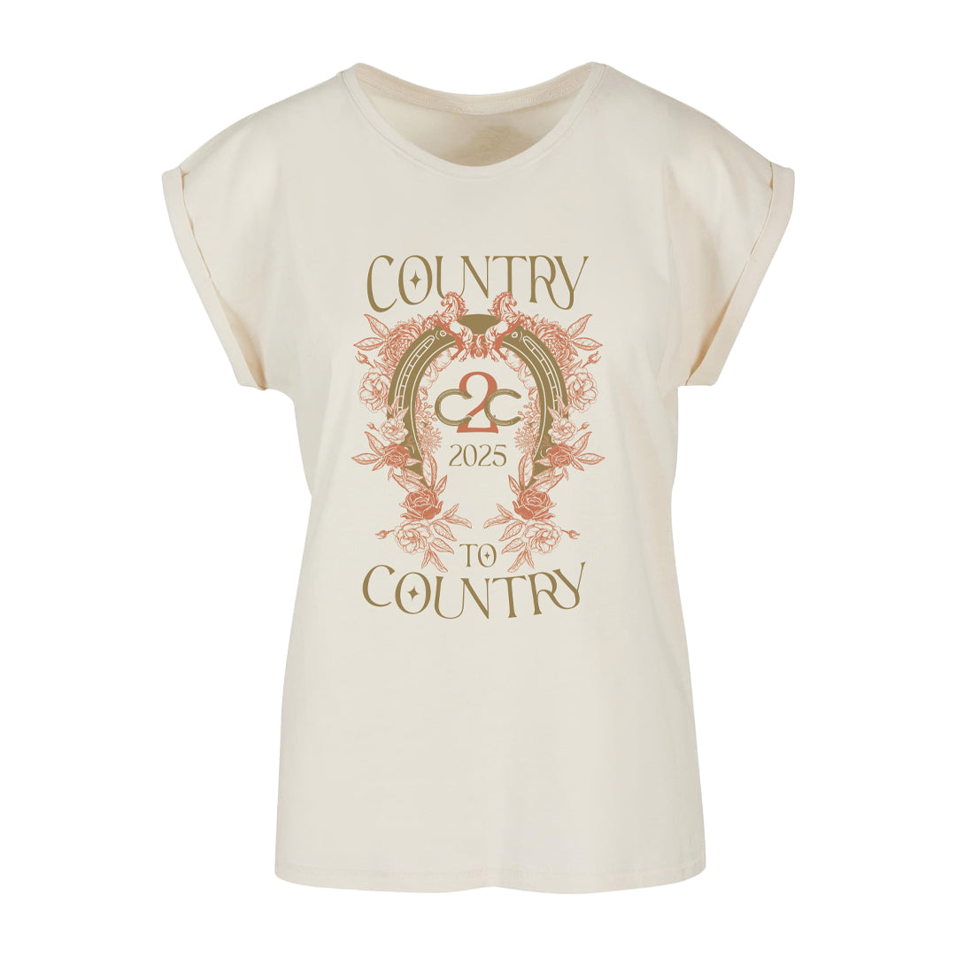 The Illustrative Ladies T-Shirt from the C2C Country To Country Store features a cream color, rolled sleeves, bird and floral design, and “Country to Country 2025” text in gold and rust—ideal for unique country concert merchandise.