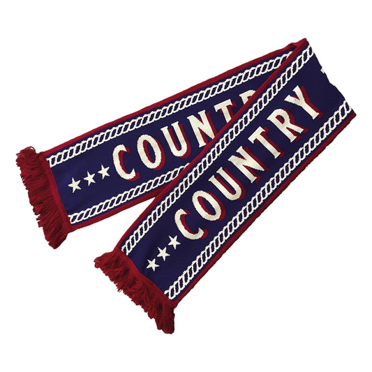 A blue scarf from C2C Country To Country Store featuring red fringe, white diagonal chains, bold COUNTRY lettering in white and red, and accents of white stars.
