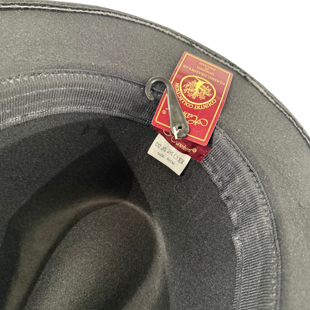 Close-up of the inside rim of a grey Cowboy Hat by 2026, featuring a red and gold “Country Collection” tag and care label with washing symbols, attached by a small metal hook.